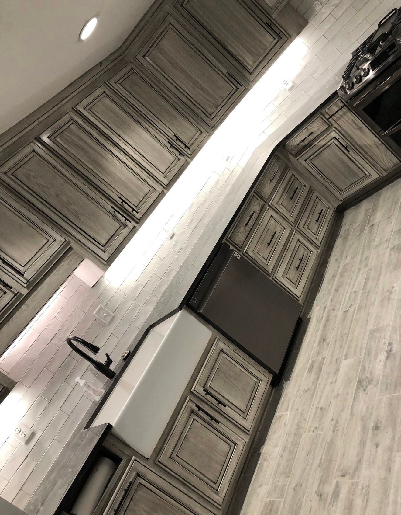 Tilting view of a modern kitchen with light cabinets, sink, and stainless steel appliances