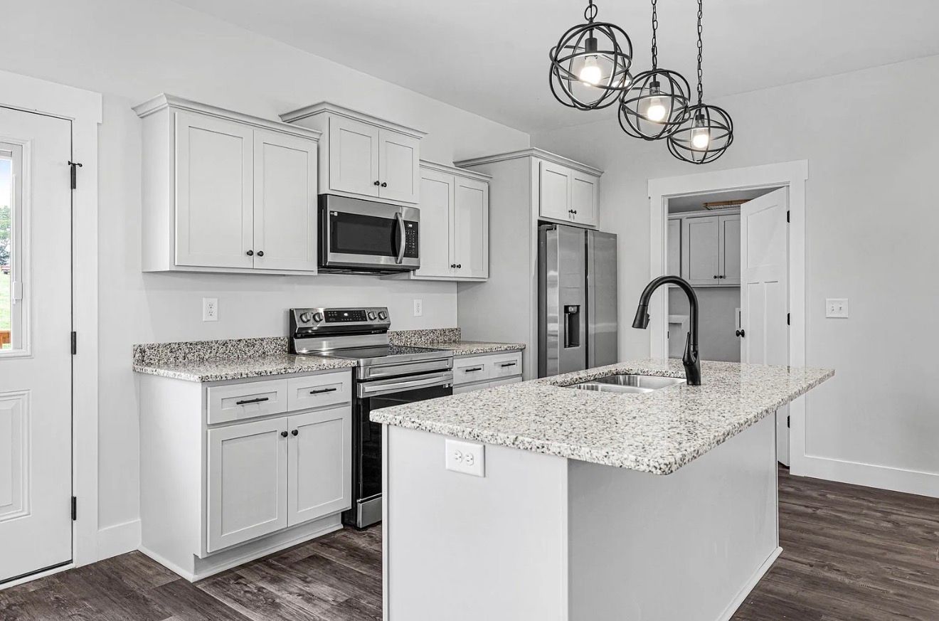 Bright modern kitchen with white cabinets, granite island, stainless appliances, and dark wood floors