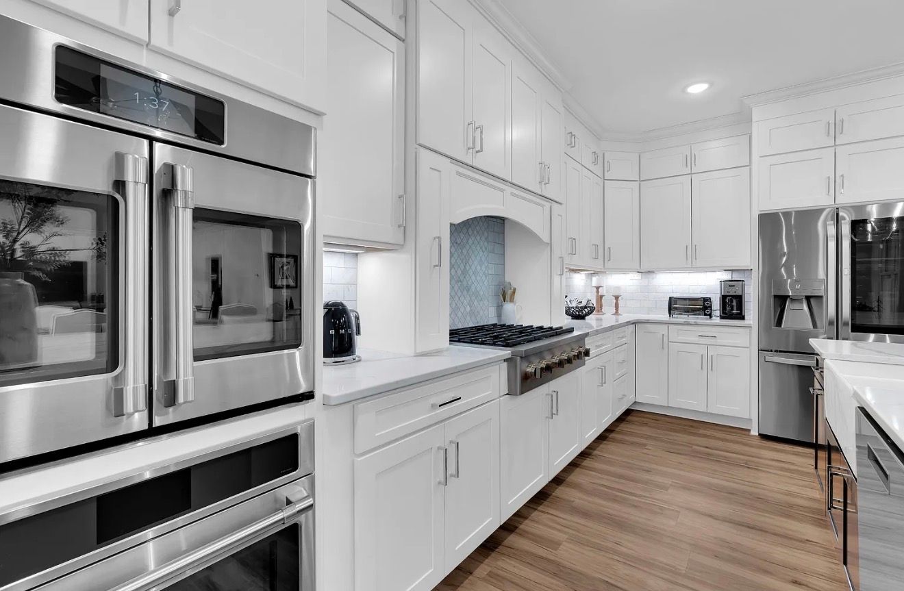 Bright white modern kitchen with stainless steel appliances and wood flooring