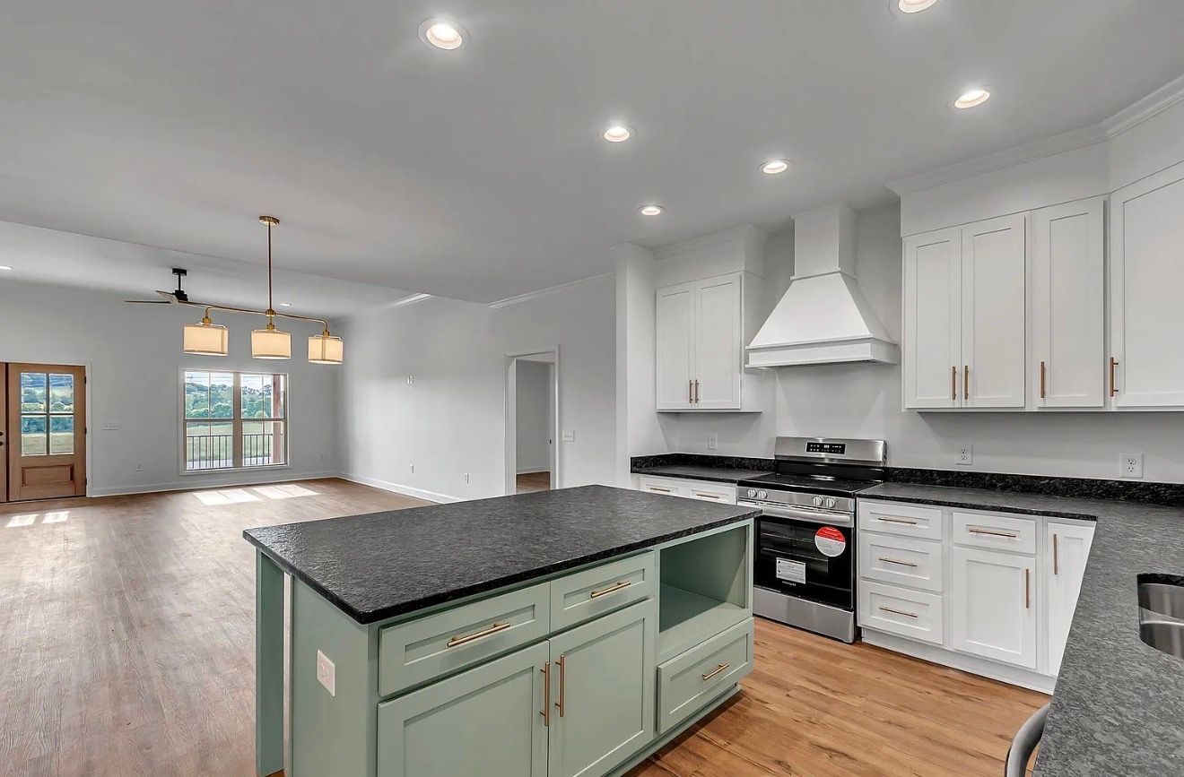 Open kitchen and living room with white cabinets, black countertops, and gray walls.