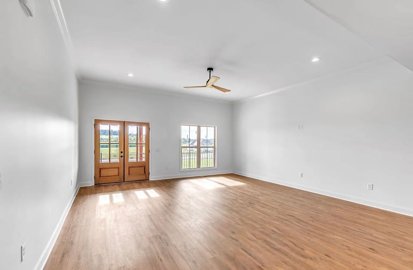 Bright empty room with hardwood floors, white walls, recessed lights, and French doors with a window.