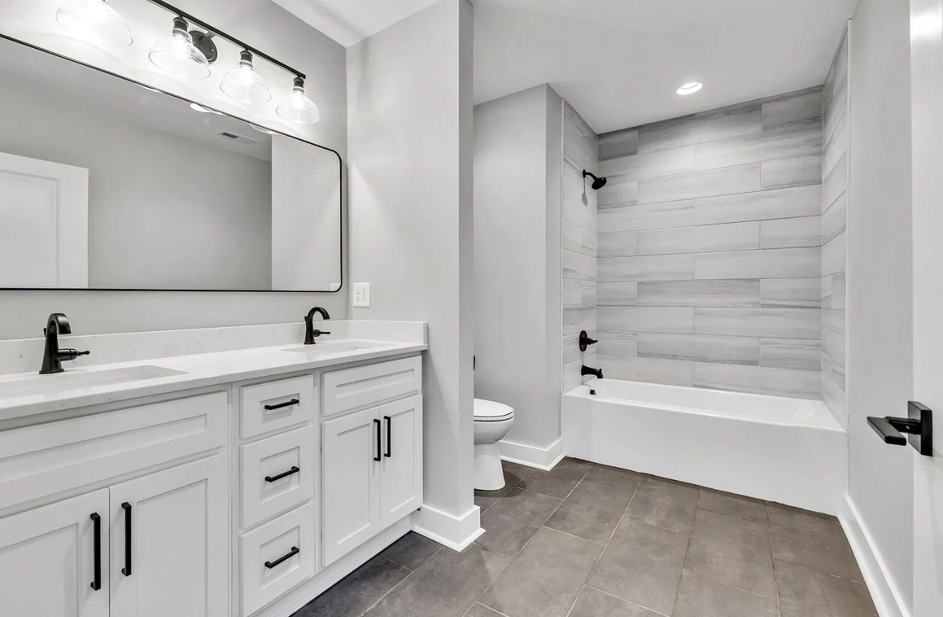 Modern bathroom with double vanity, large mirror, and tiled shower-bathtub combo