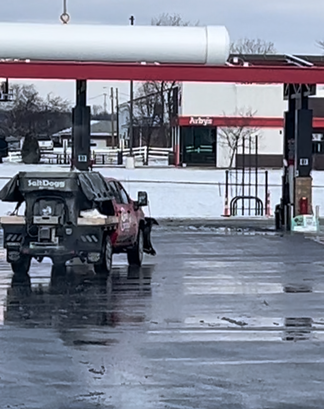 a red truck is parked in a parking lot at a gas station