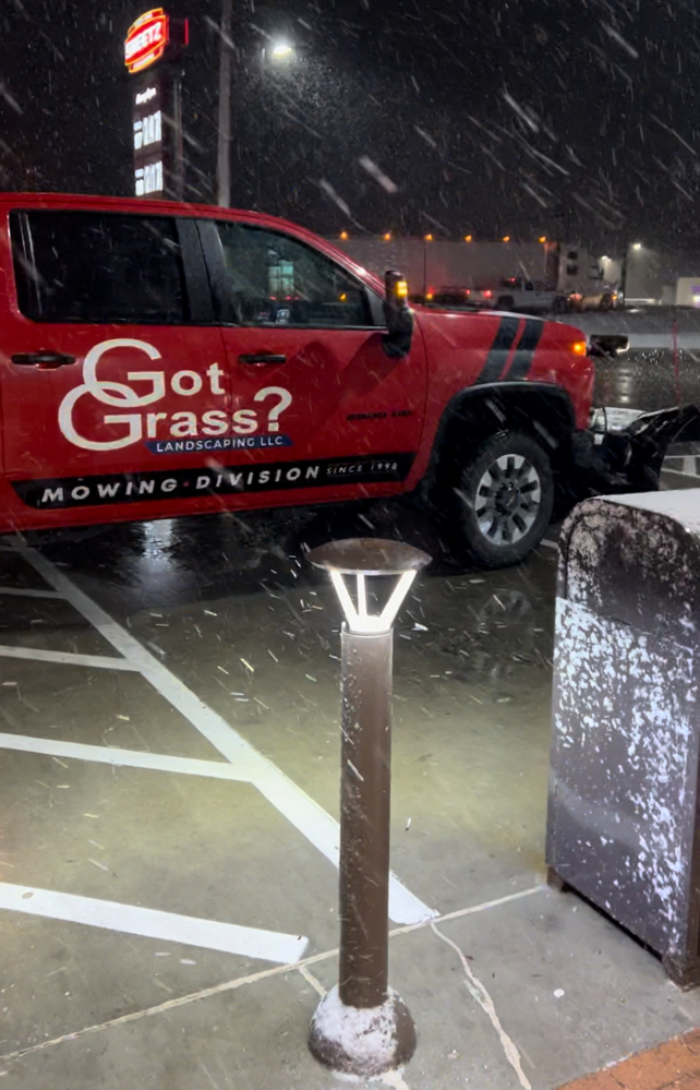 a red truck that says got grass is parked in a parking lot