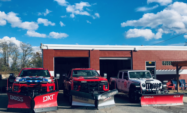 three snow plows are parked in front of a brick building .