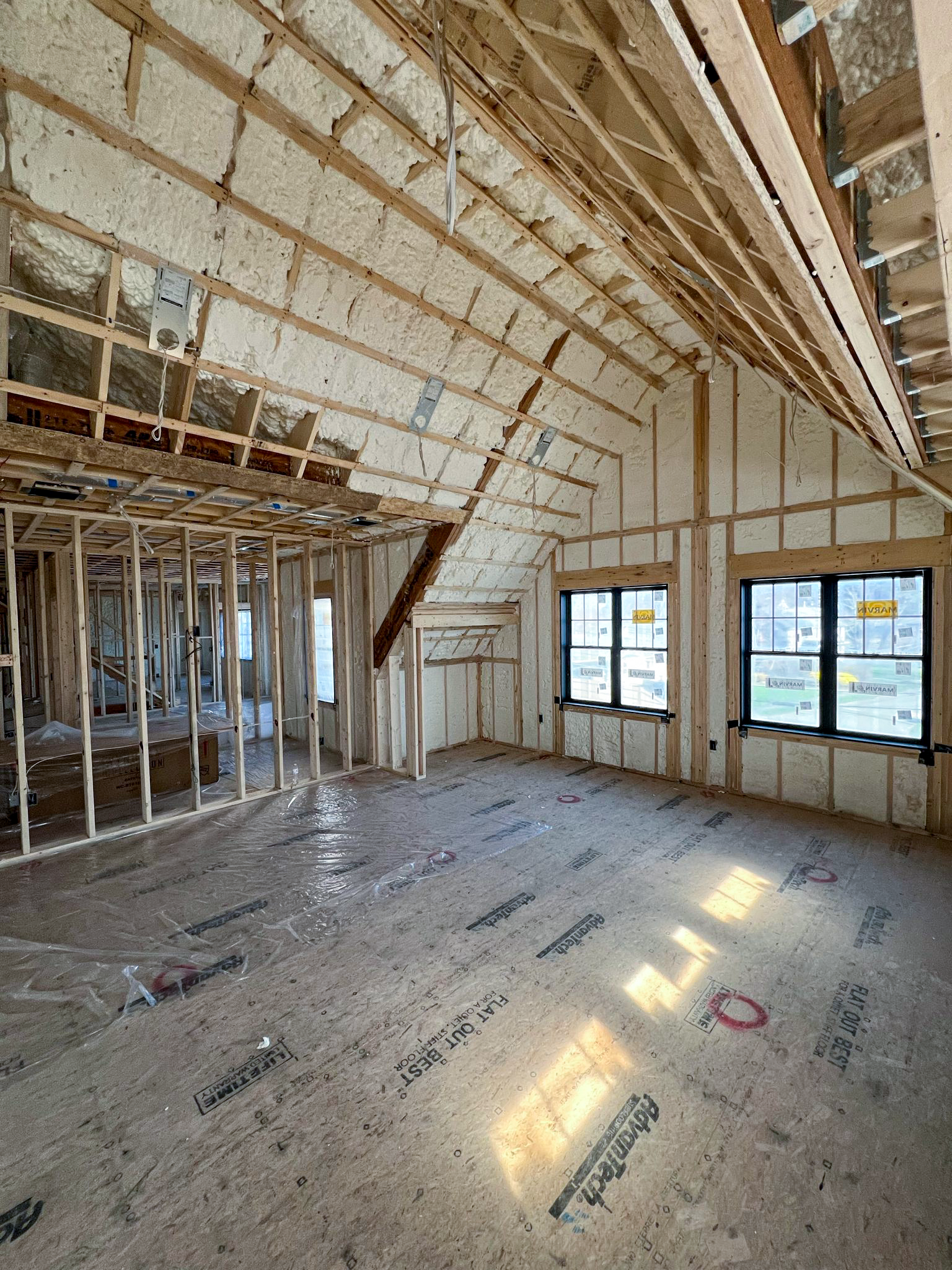 A room in a house under construction with a lot of windows.
