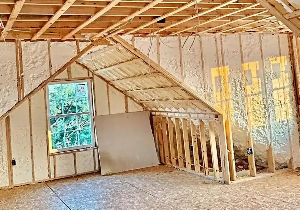 An attic under construction with foam insulation and a window.