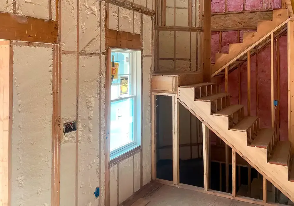 A room with stairs and a window in a house under construction.