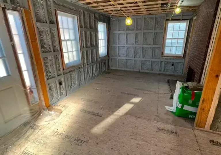 A room with a lot of windows and a green bag on the floor.