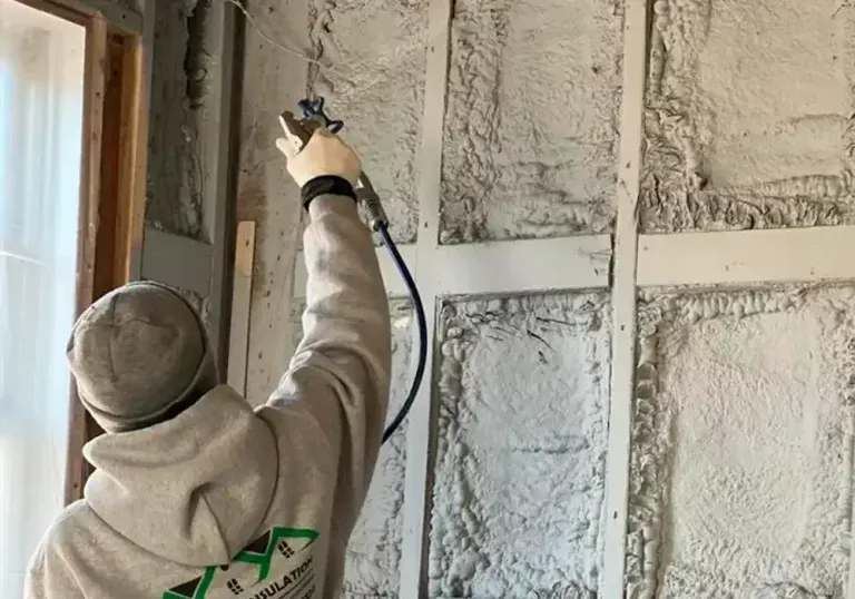 A man is spraying foam on a wall.