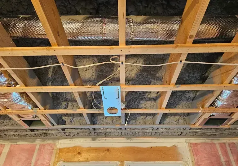 The ceiling of a house is being built and there is a hole in the ceiling.