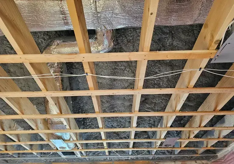 The ceiling of a building under construction with wooden beams and insulation.