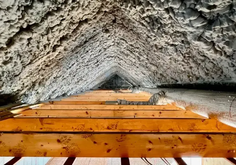 Looking up at the ceiling of an attic with wooden beams.