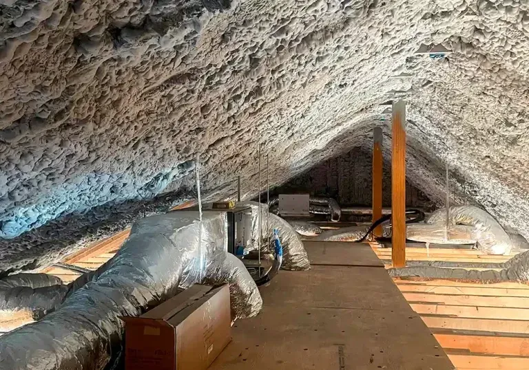 An attic with a lot of ducts and pipes in it.
