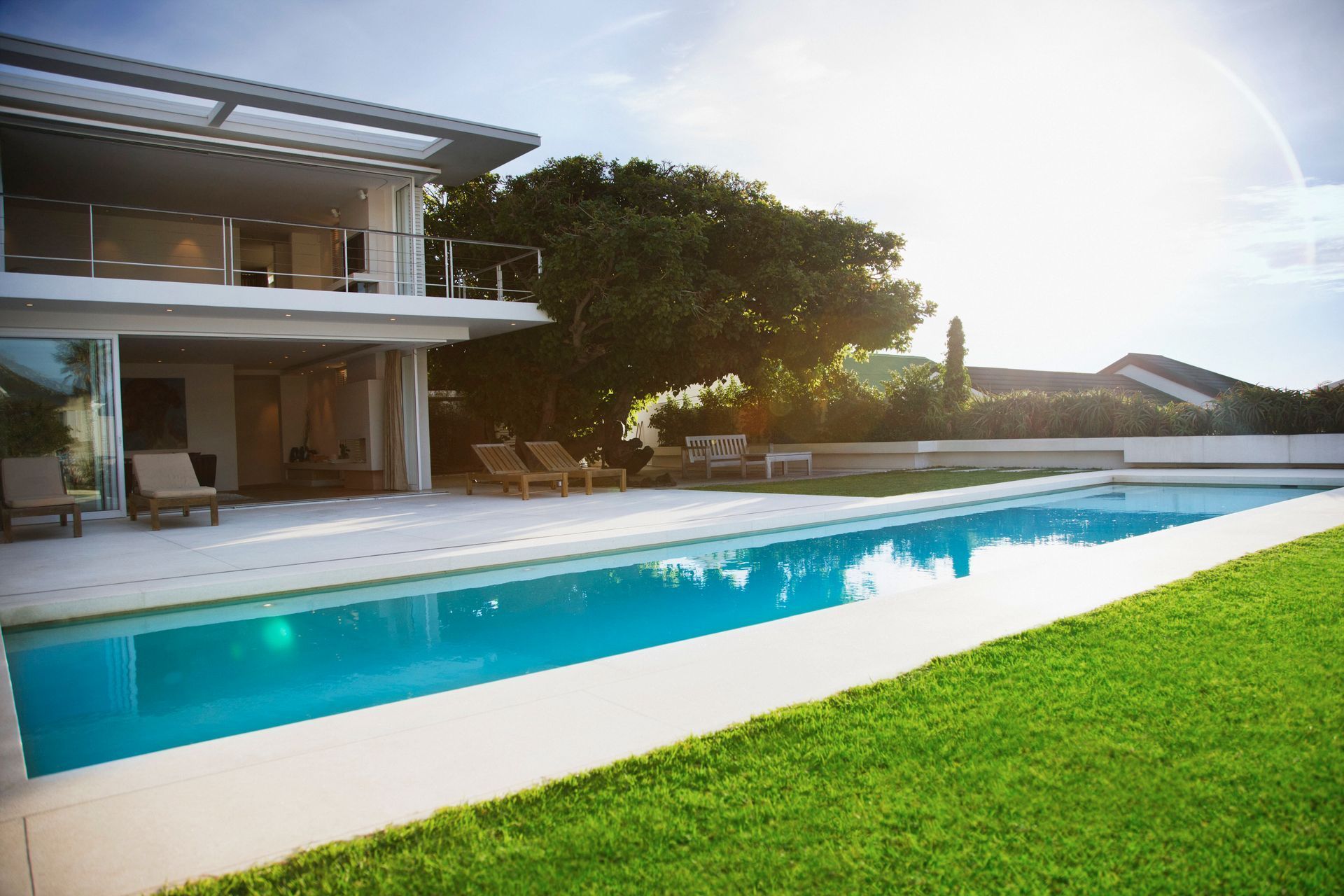 Modern house with a long rectangular pool, sunny outdoor setting.