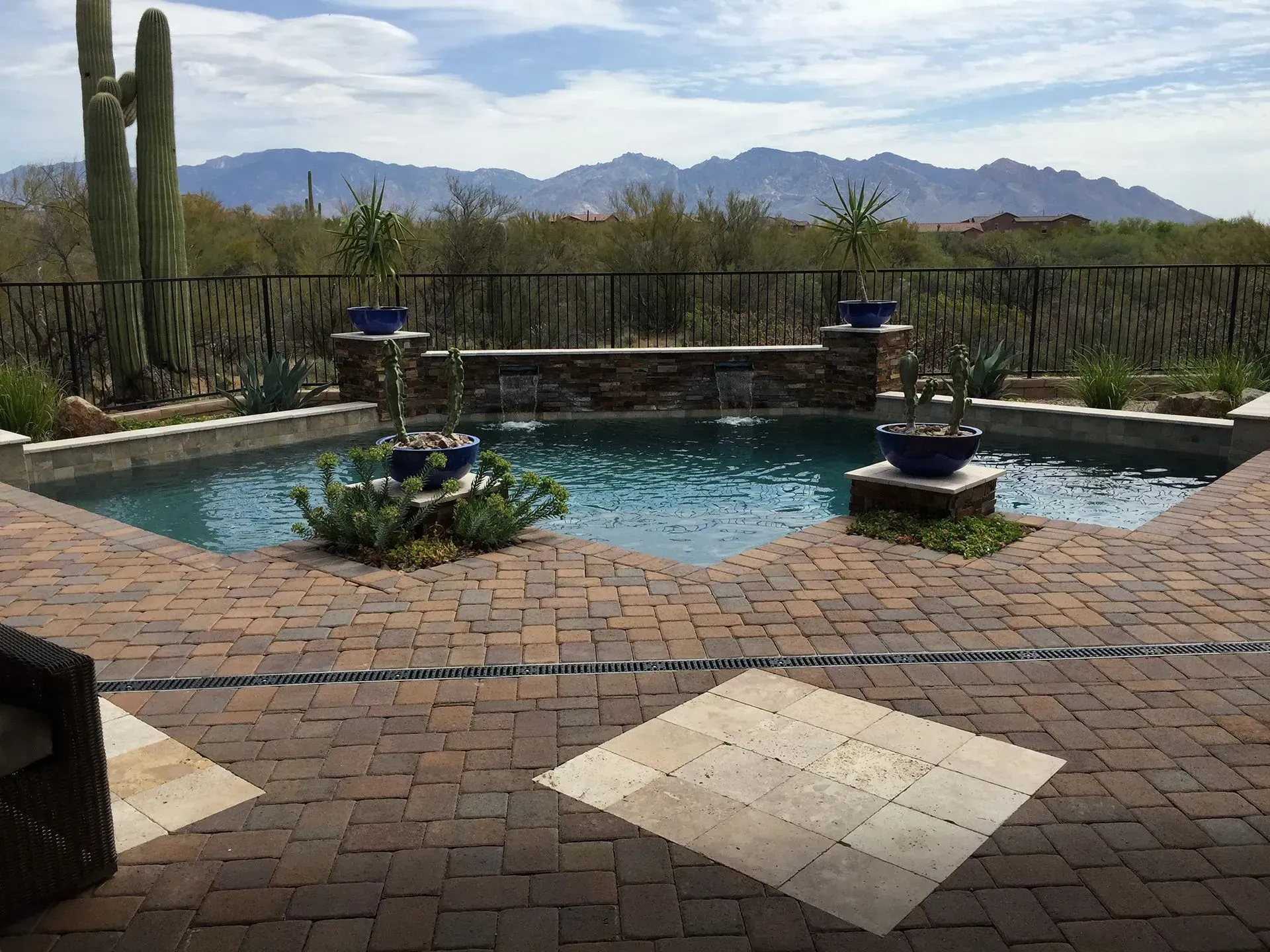 Pool with waterfall feature and brick patio, desert landscape, mountains in background.