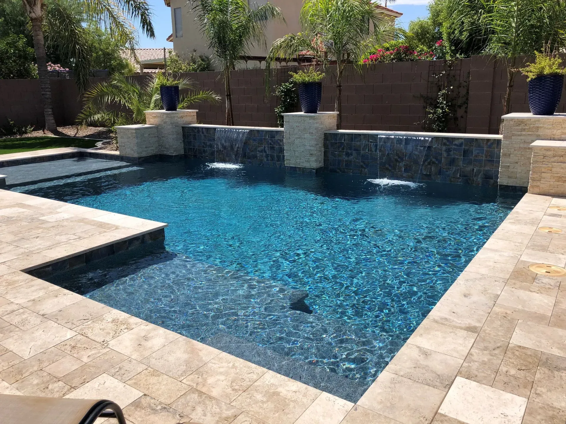 Pool with cascading waterfalls and blue water surrounded by stone pavers.