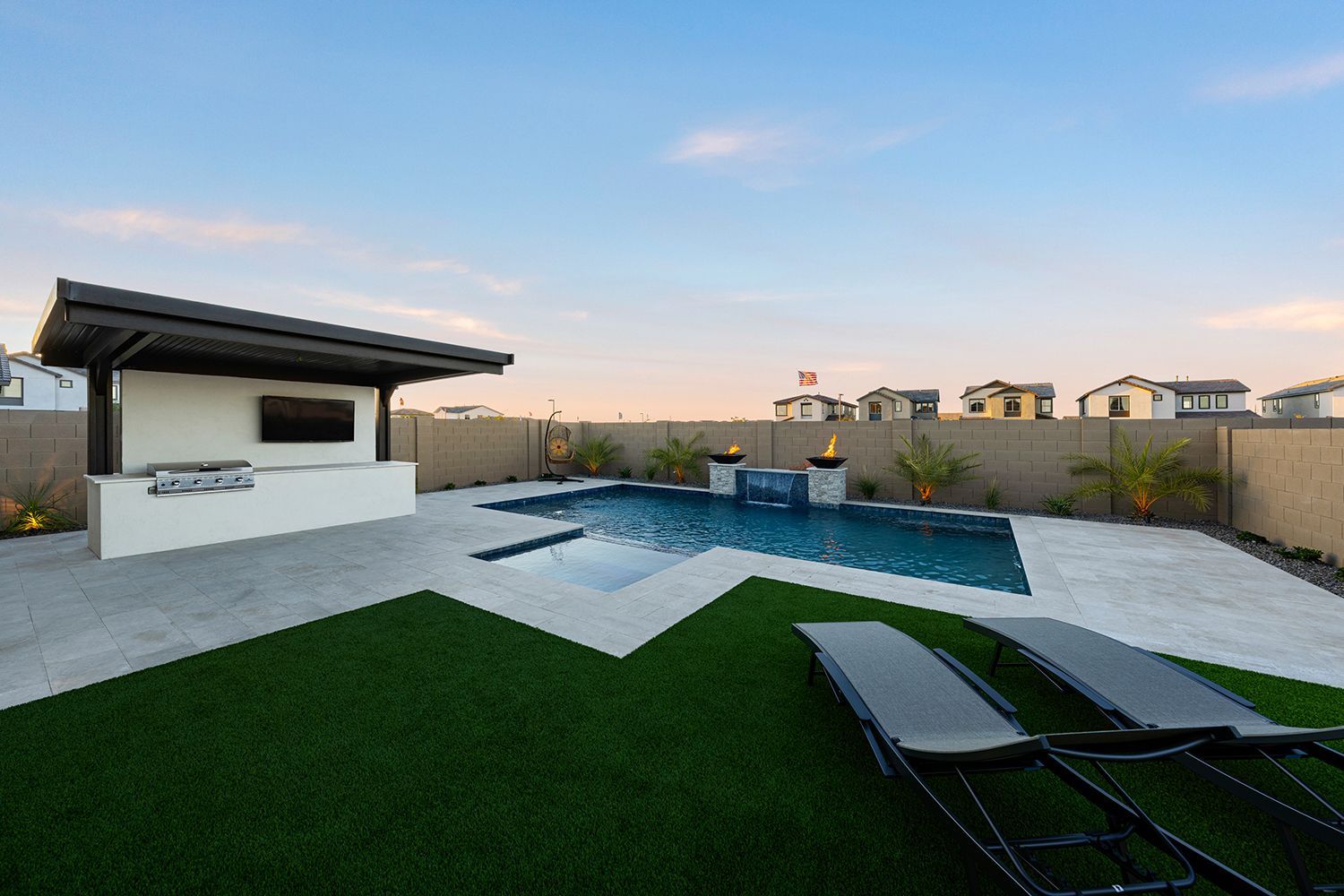 Backyard with pool, outdoor kitchen, lounge chairs, and artificial turf.