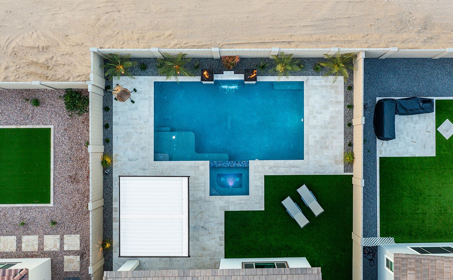 Overhead view of a rectangular pool with surrounding patio, grass, and a pergola in a backyard setting.