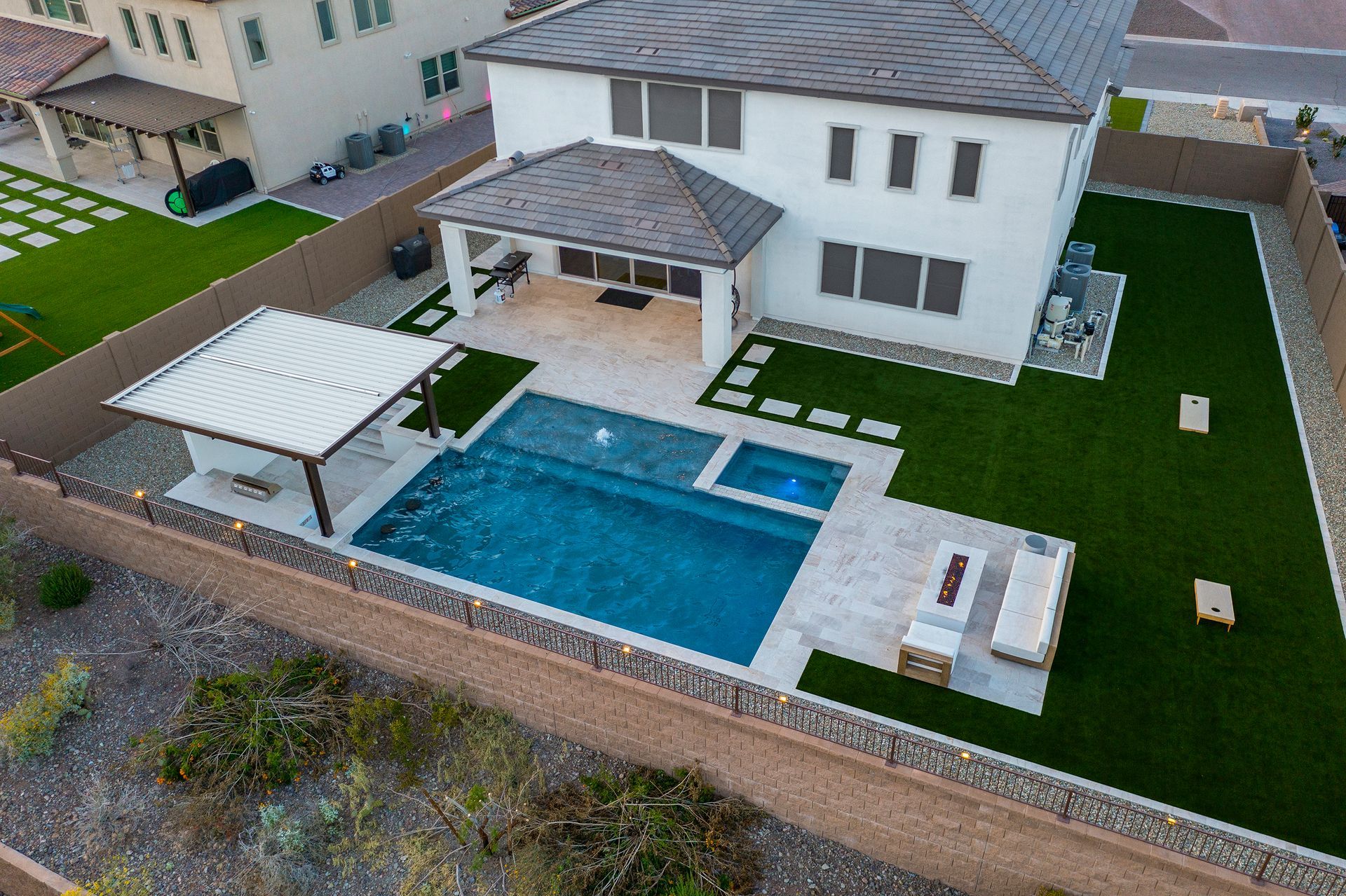 Aerial view of a modern house with a pool, patio, and green artificial turf.