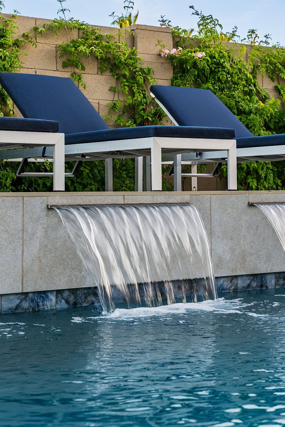Pool with waterfall feature and lounge chairs.