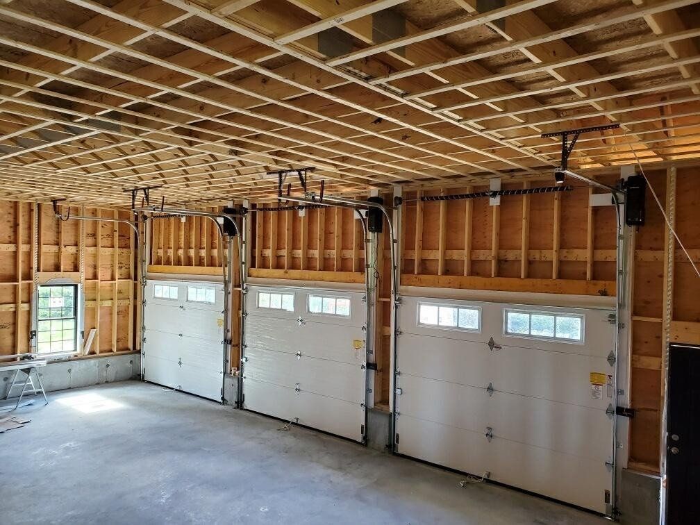 Unfinished garage interior with three white garage doors