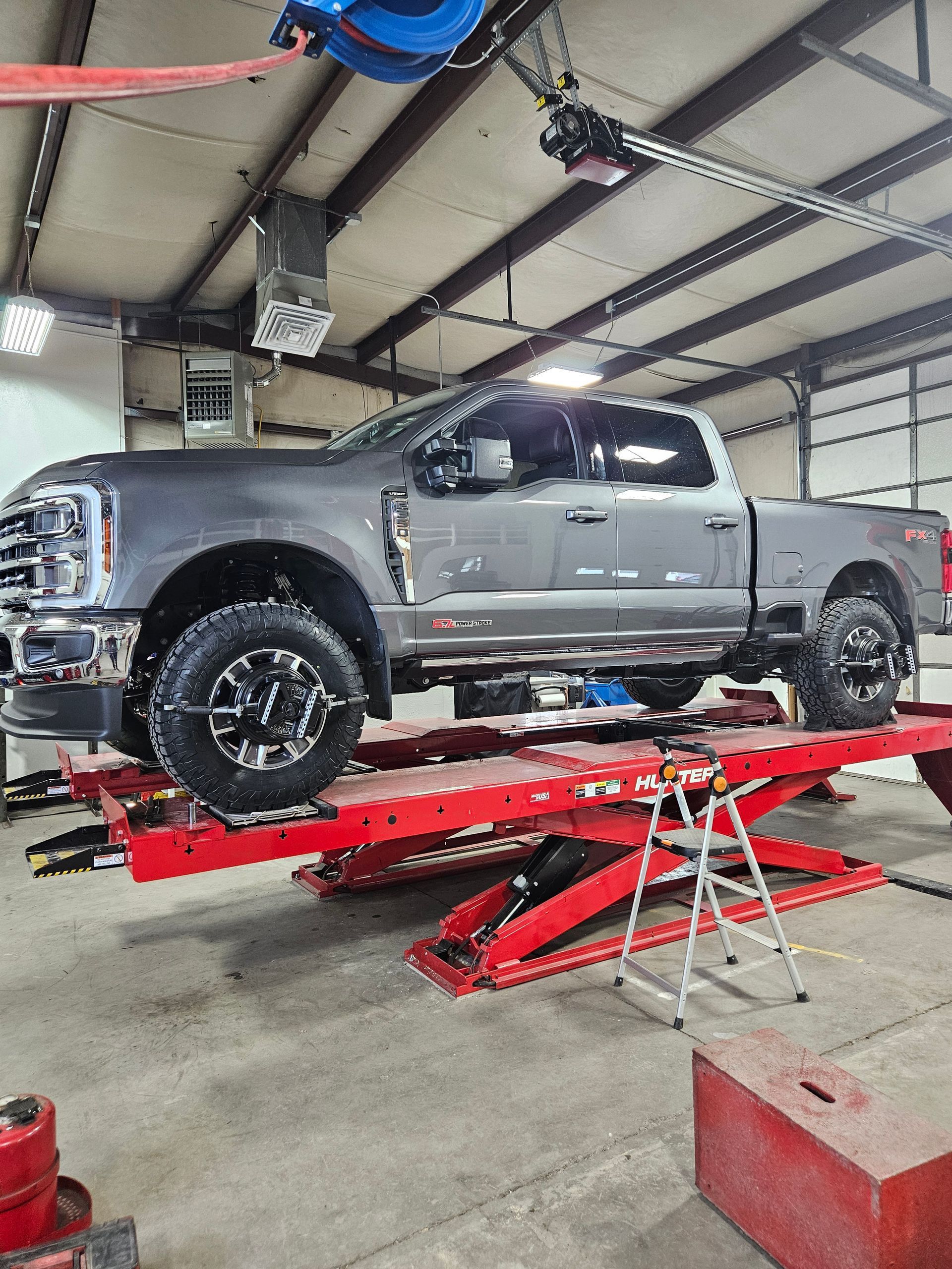 A gray truck is sitting on top of a red lift in a garage