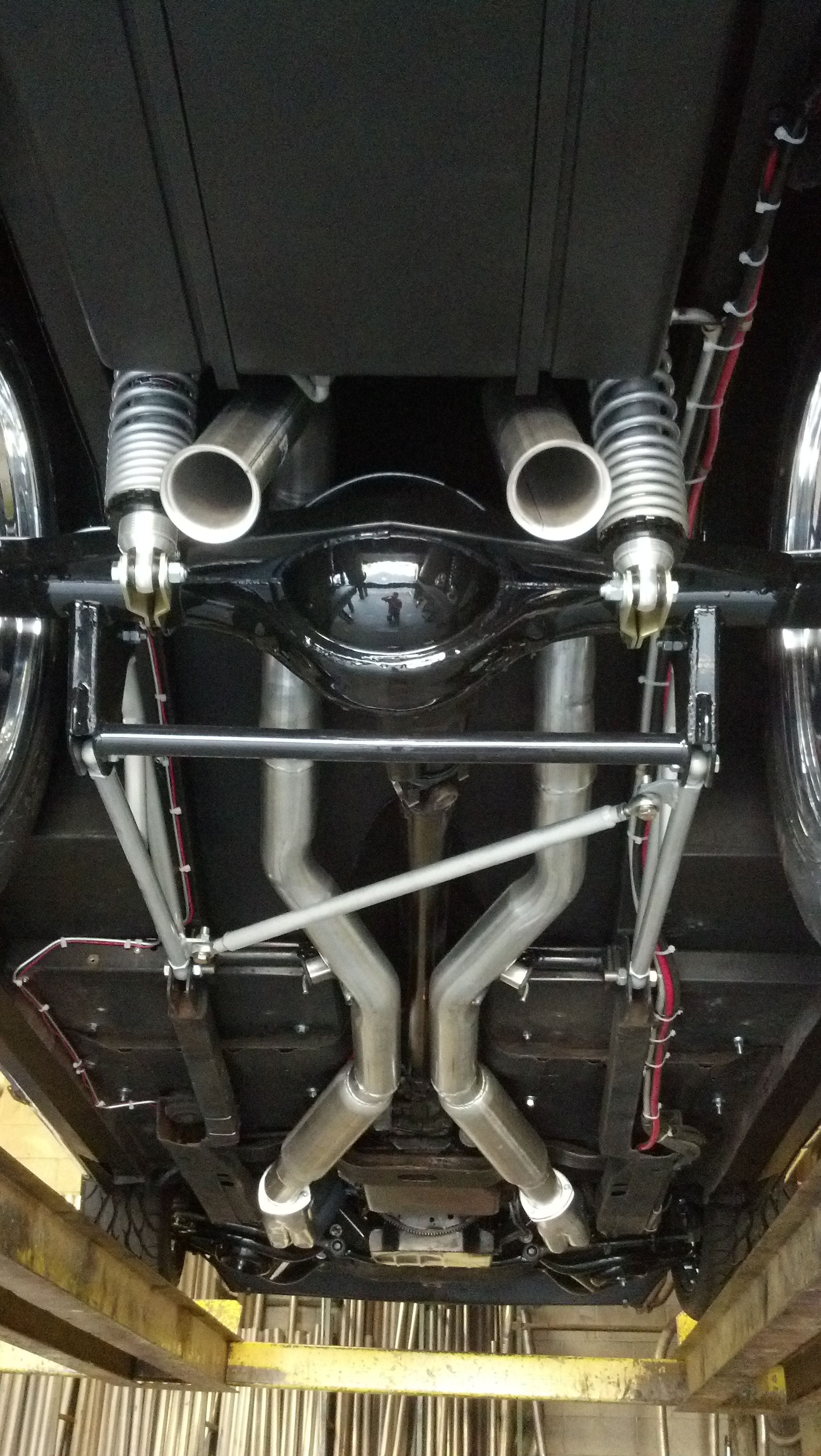 The underside of a car is shown in a garage.