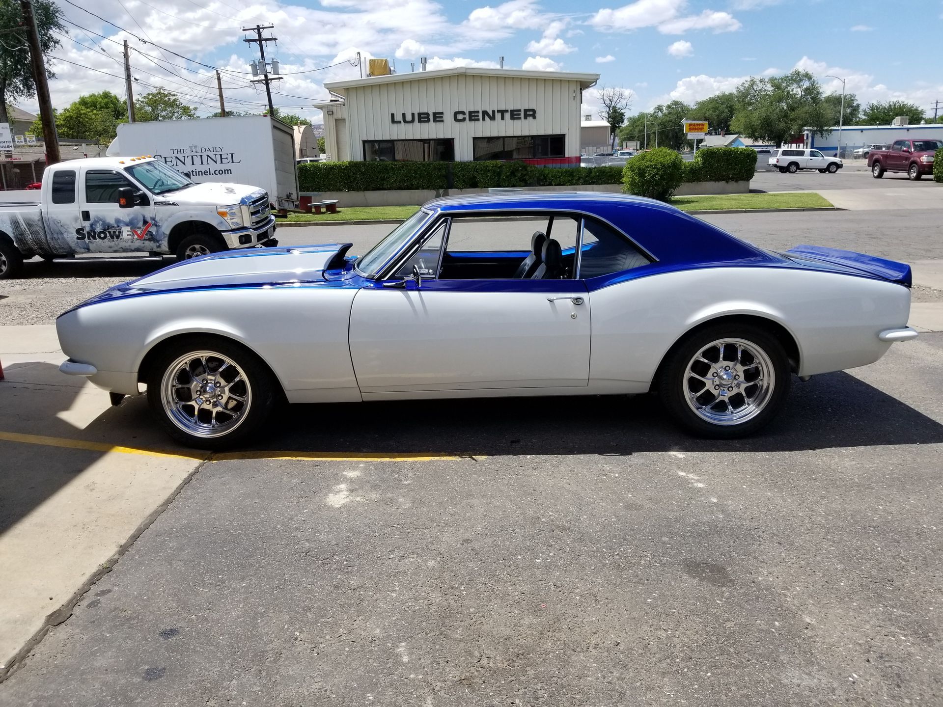 A white and blue car is parked in front of a lube center