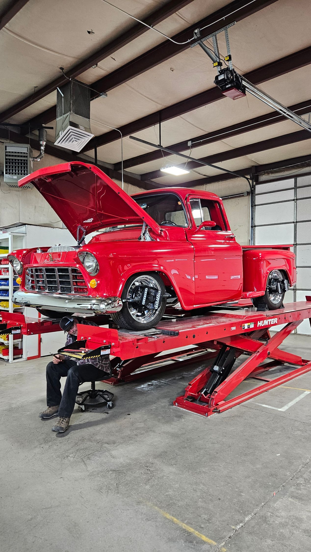 A red truck is sitting on top of a red lift in a garage.