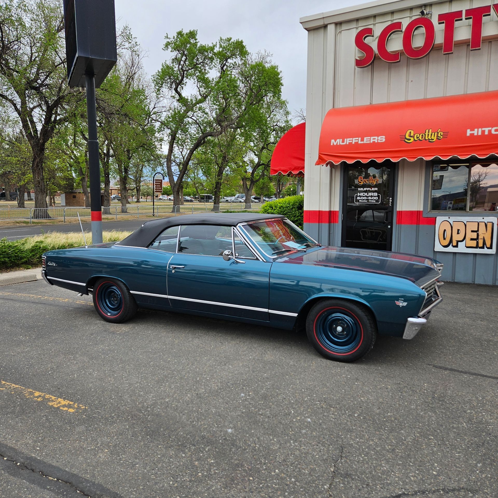 A blue car is parked in front of scott 's