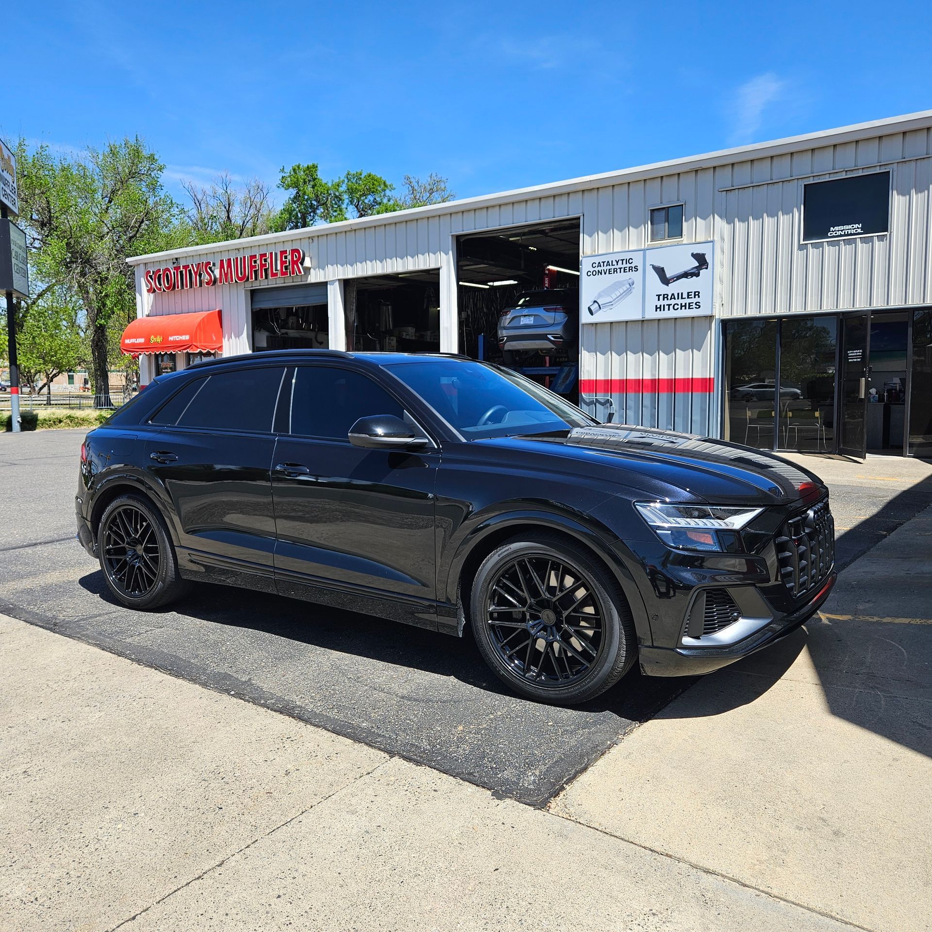A black car is parked in front of a garage.