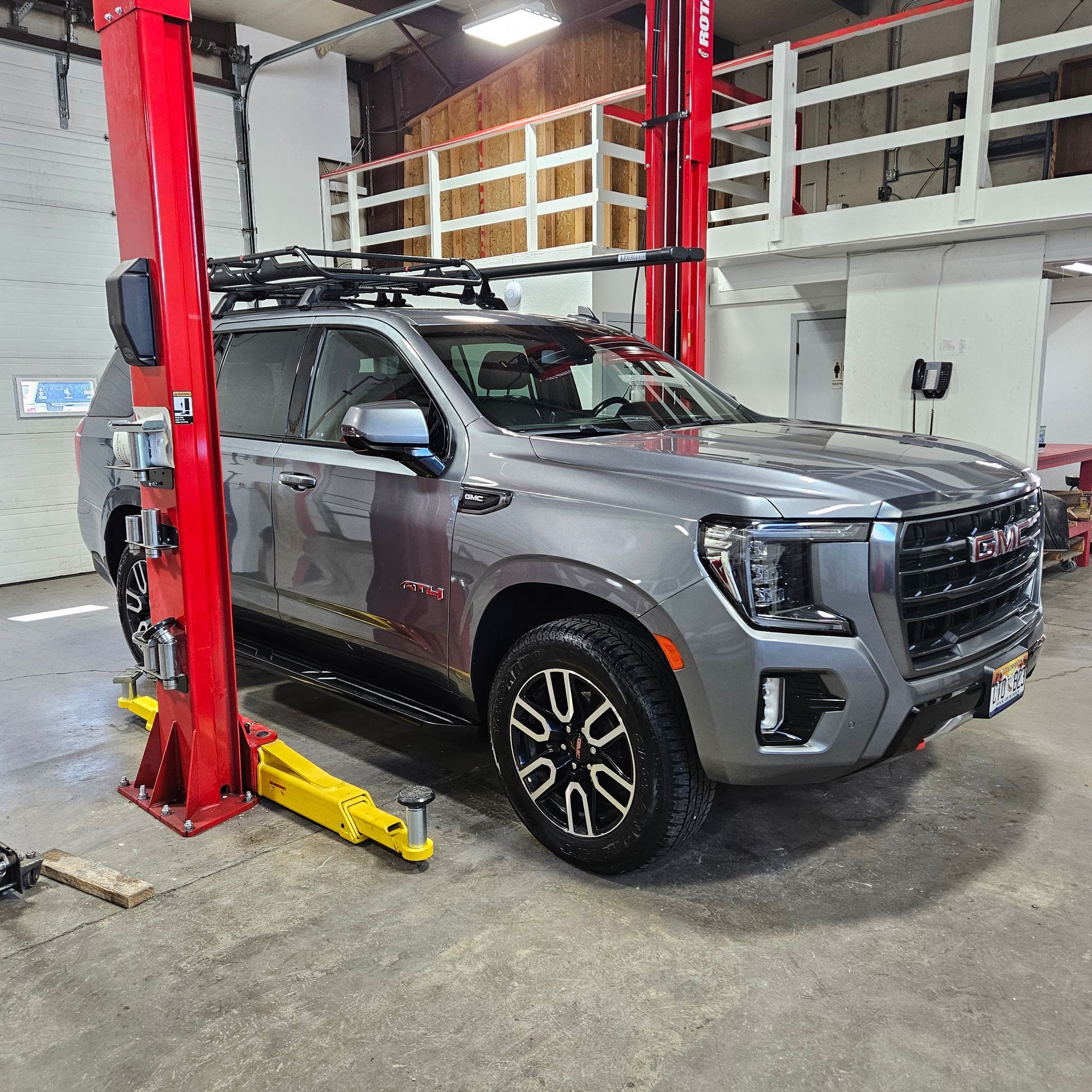 A gray suv is parked on a lift in a garage.