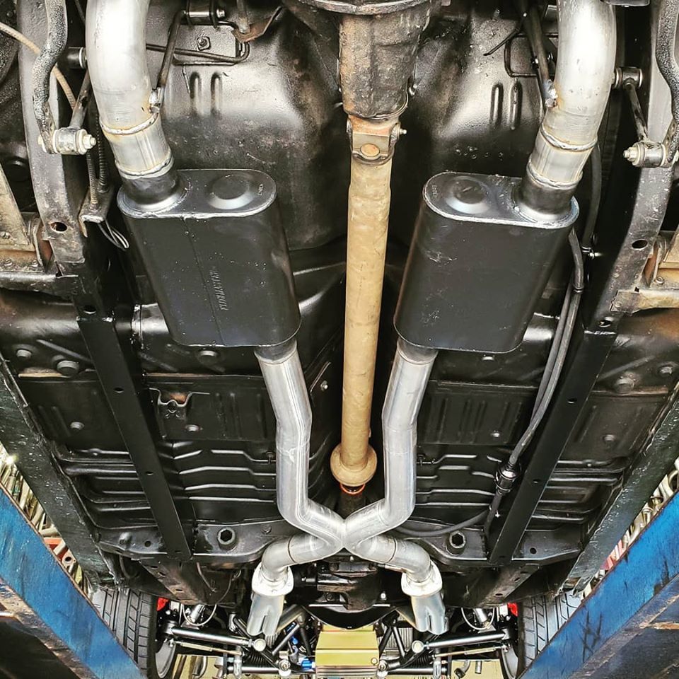 A close up of the underside of a car with exhaust pipes.