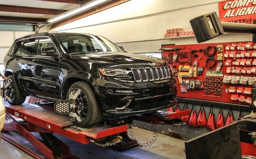 A black jeep grand cherokee is sitting on a lift in a garage.