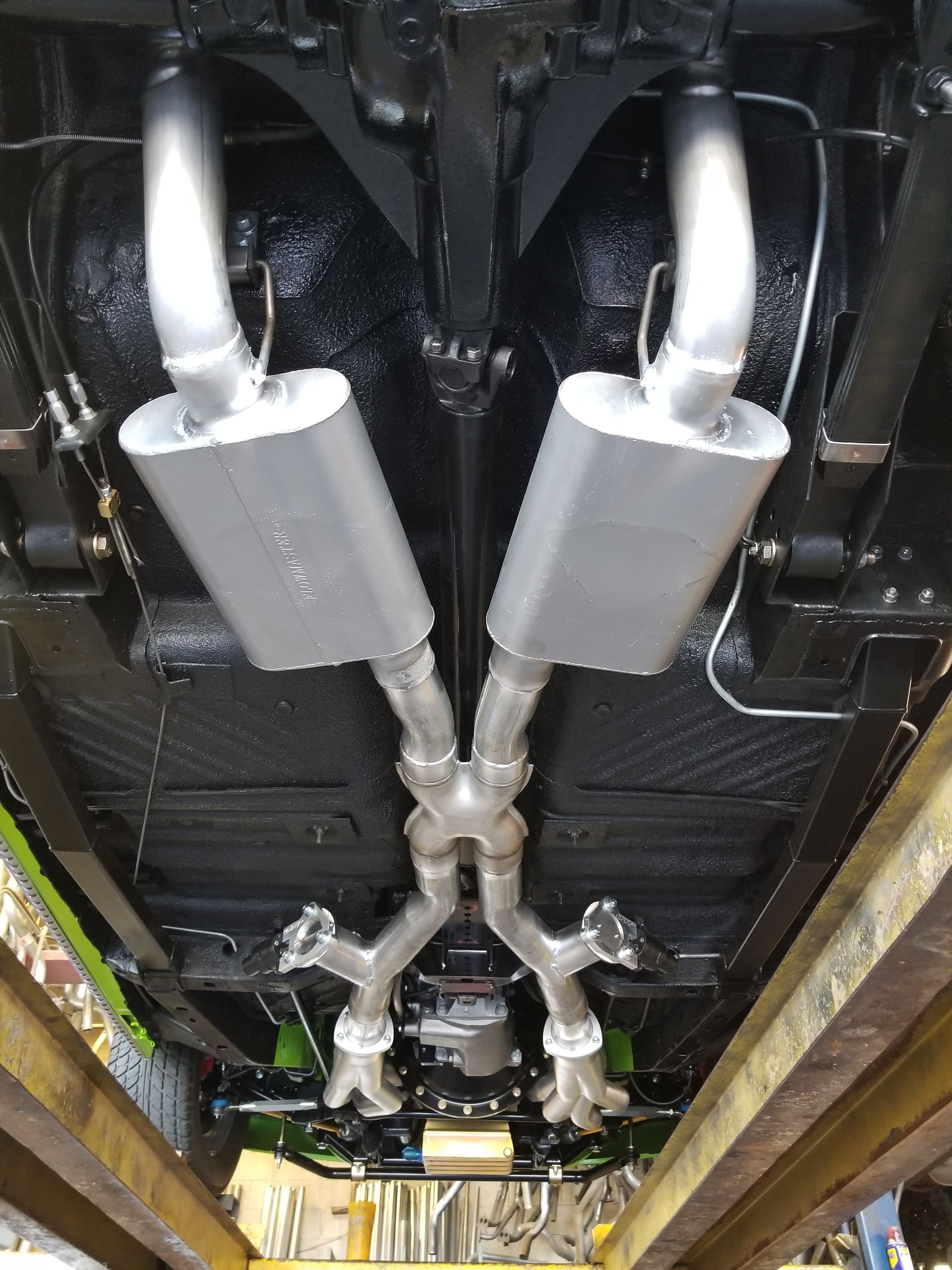 The exhaust pipes of a car are visible underneath it.