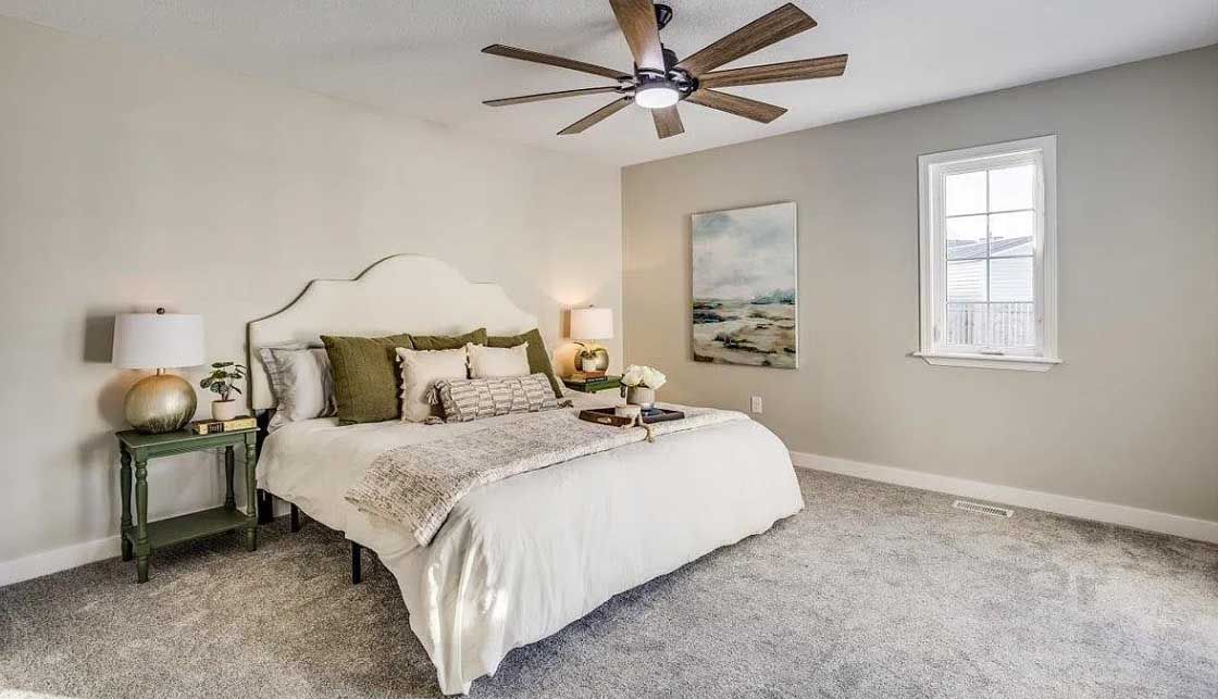 A bedroom with a bed and a ceiling fan.