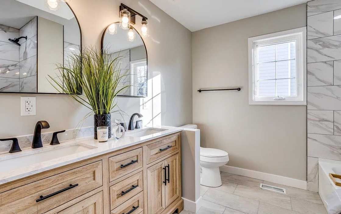 A bathroom with two sinks , a toilet , and a window.