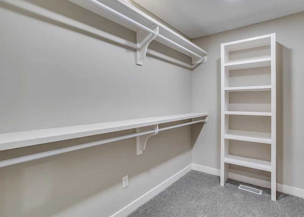 An empty walk in closet with shelves and a ladder.