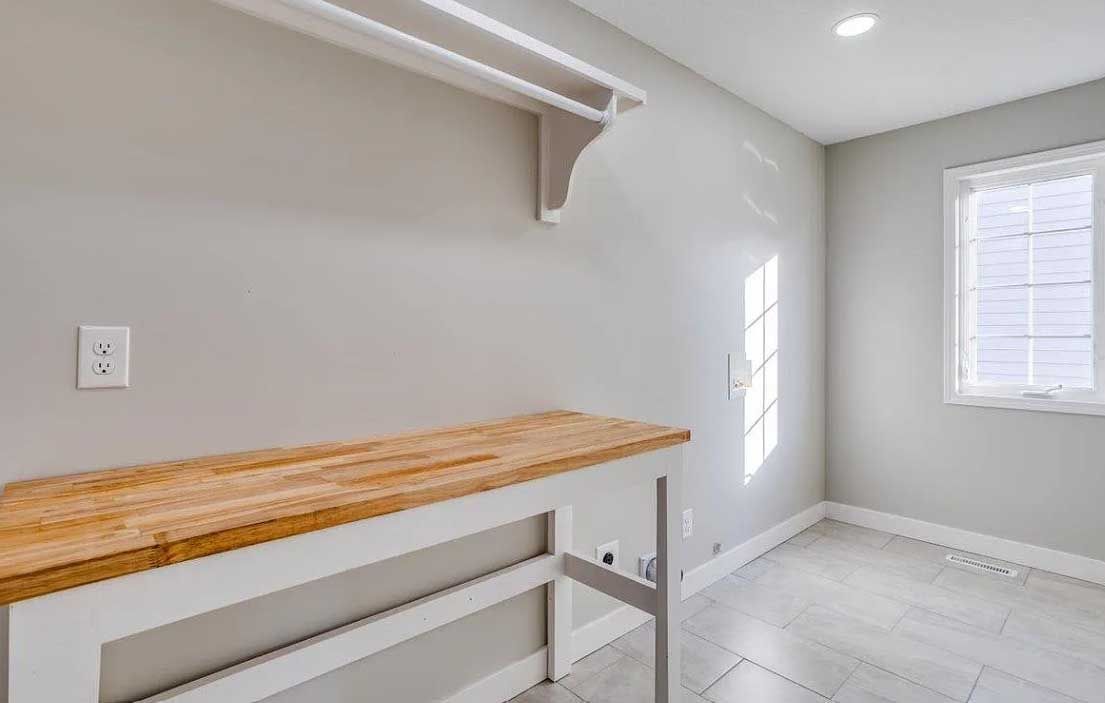 A laundry room with a wooden table and a window.