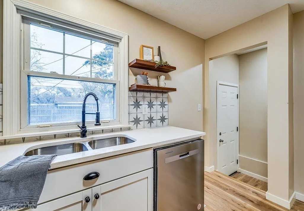 A kitchen with a sink , dishwasher , and window.