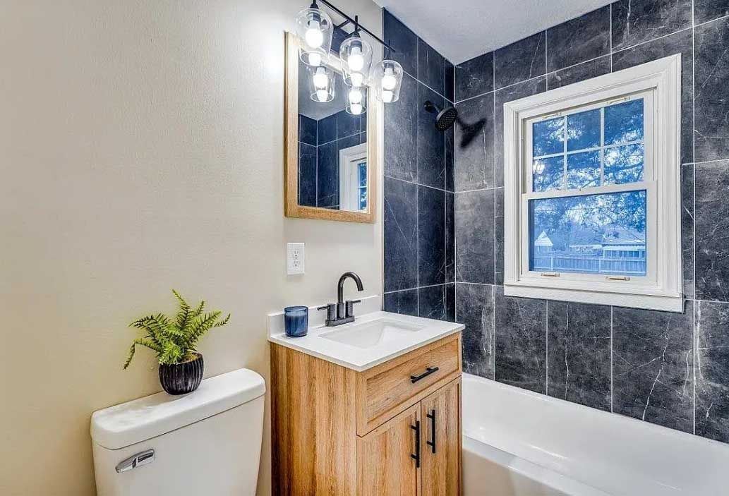 A bathroom with a toilet , sink , mirror and tub.