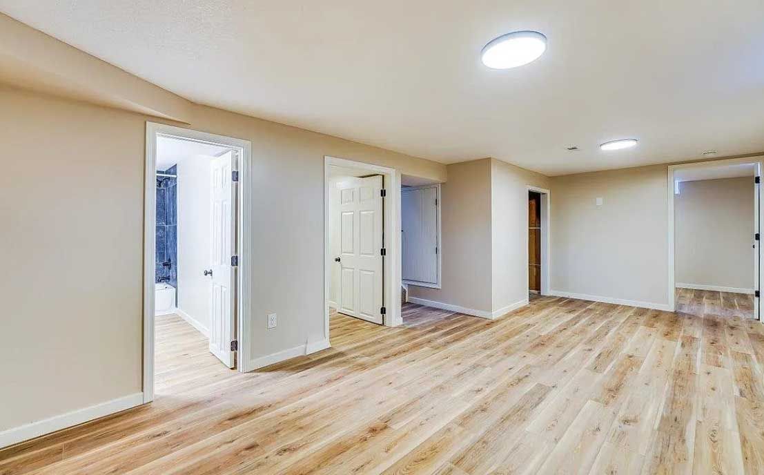 A large empty room with hardwood floors and white walls.