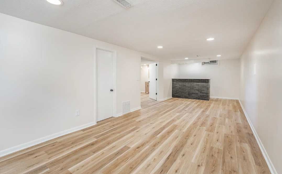 An empty living room with hardwood floors and white walls.
