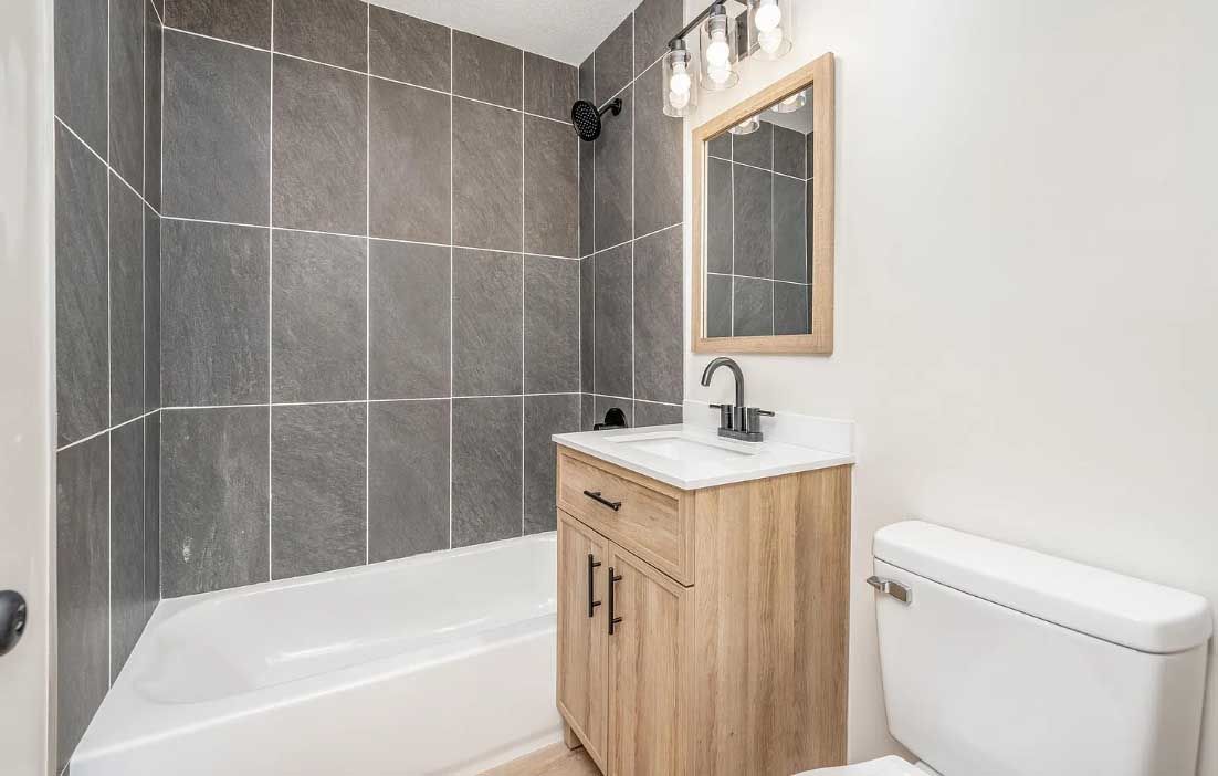 A bathroom with a sink , toilet , bathtub and mirror.