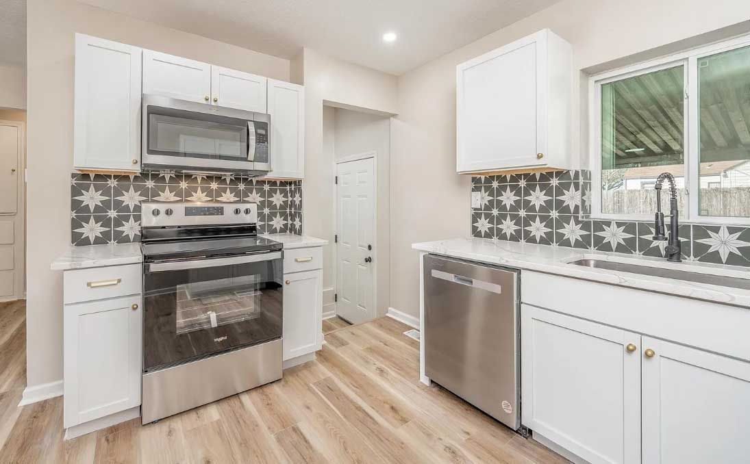 A kitchen with stainless steel appliances and white cabinets.