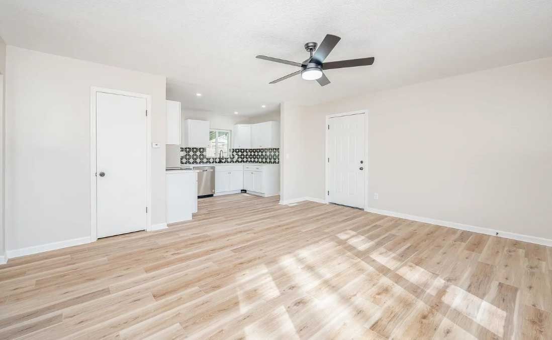 An empty living room with hardwood floors and a ceiling fan.