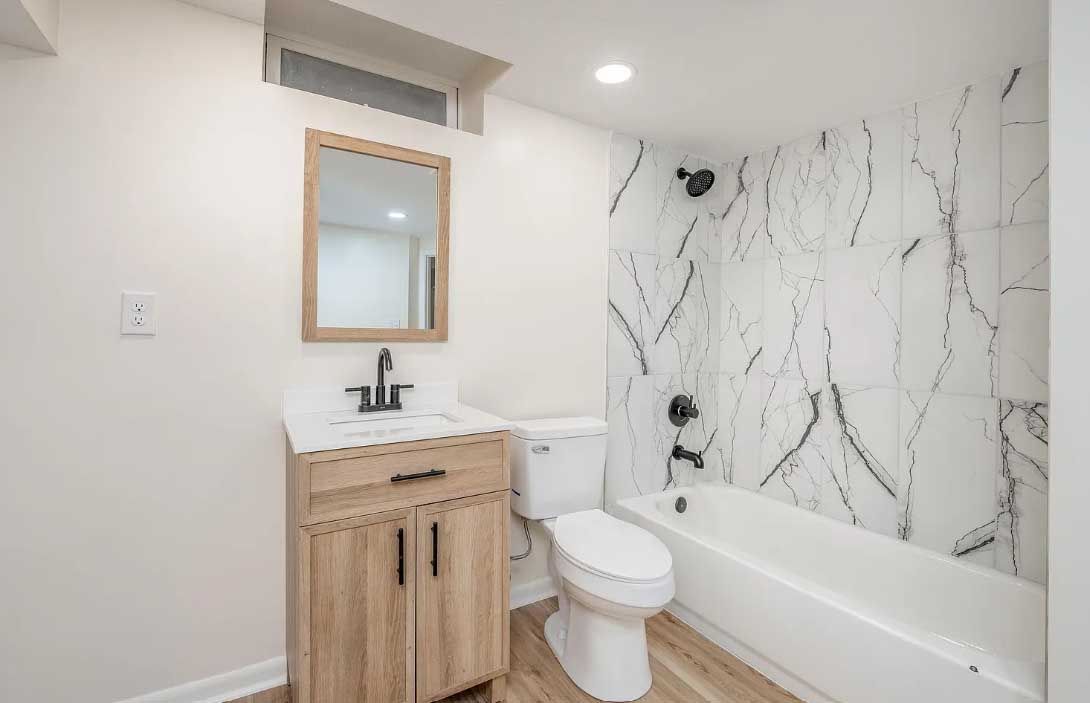 A bathroom with a toilet , sink , mirror and bathtub.
