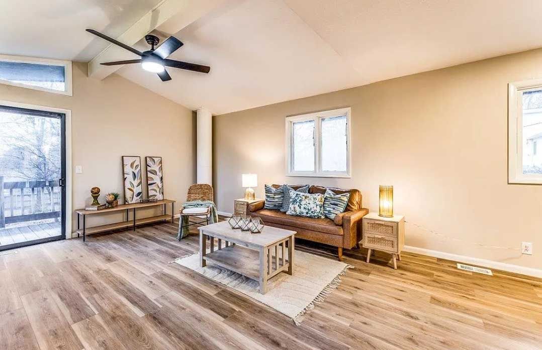 A living room with a couch , chair , coffee table and ceiling fan.