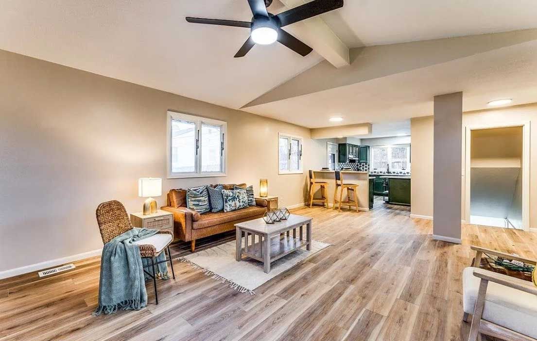 A living room with a couch , chairs , coffee table and ceiling fan.
